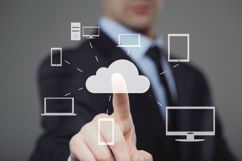 Businessman points at illustration of cloud connected to different devices